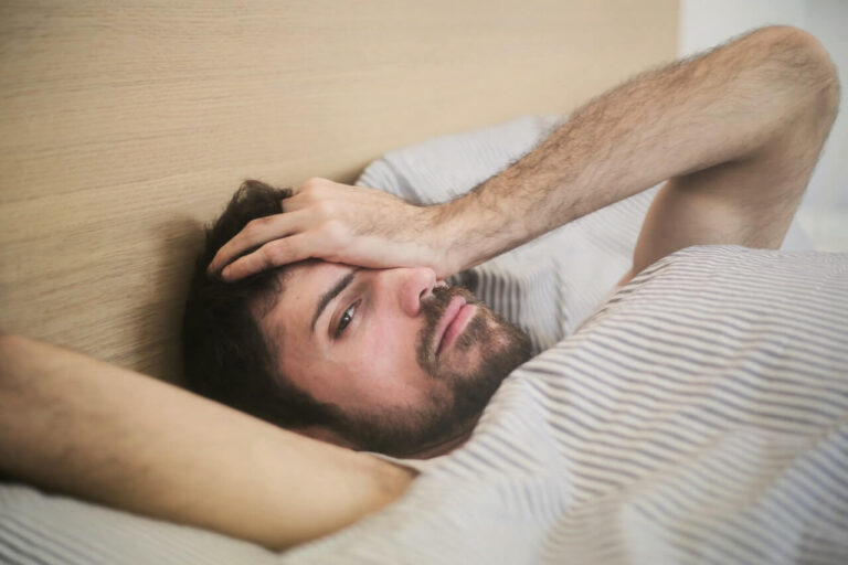 hombre joven recostado en cama que no puede dormir