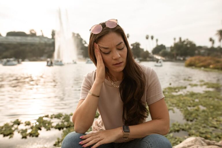 Mujer sentada en parque con rostro triste y distante